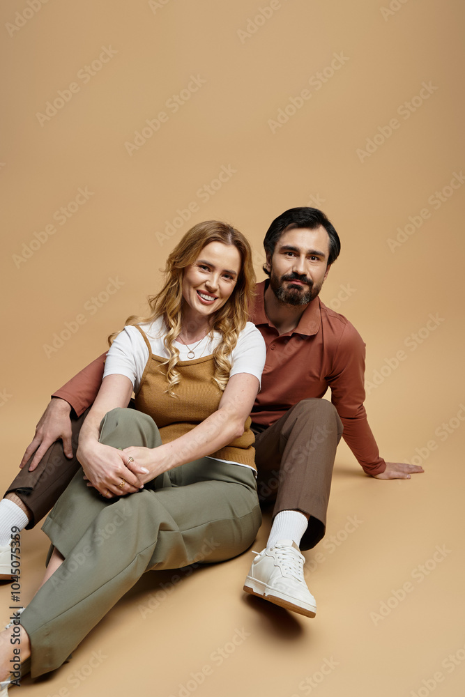 A joyful middle aged couple relaxes in stylish outfits against a soft backdrop. A joyful middle aged couple relaxes in stylish outfits against a soft backdrop.