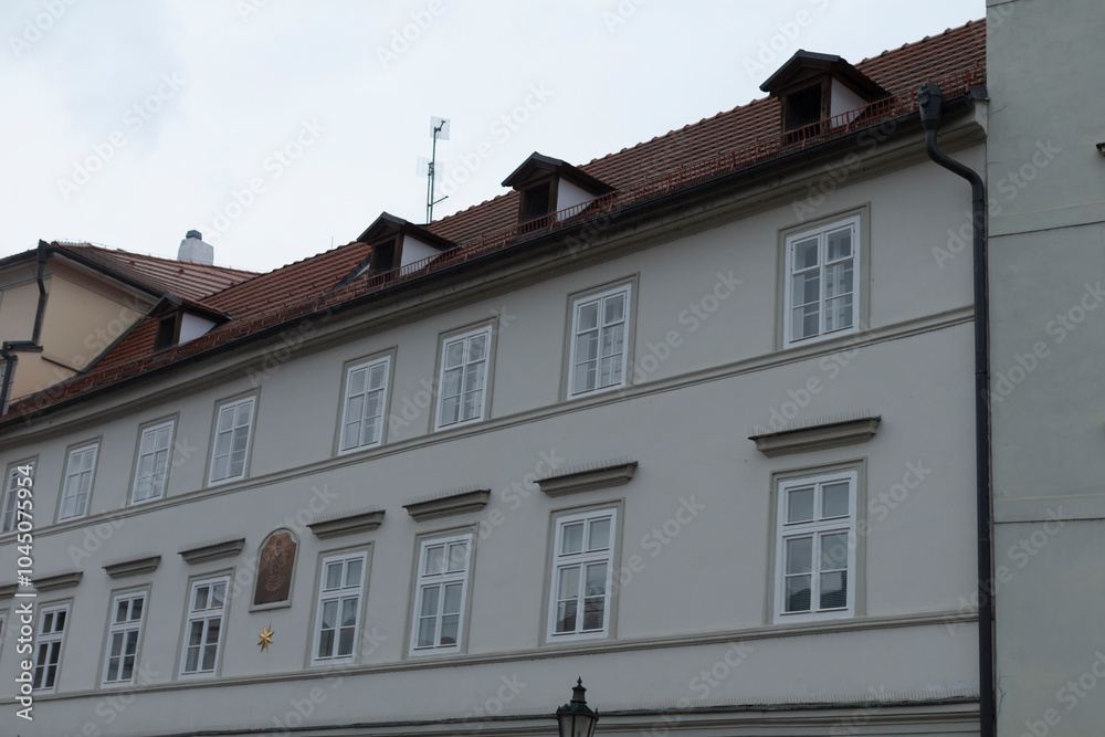Fototapeta premium In the landscape stands a large, impressive white building, adorned with a striking red tiled roof that captures the eye of onlookers