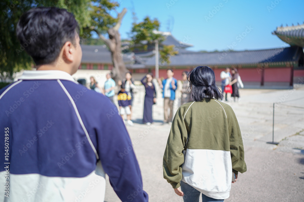 A Korean couple, a man in his 30s and a woman in her 20s, walks harmoniously through a historical building in Seoul, South Korea, wearing Hanbok. A Korean couple, a man in his 30s and a woman in her 20s, walks harmoniously through a historical building in Seoul, South Korea, wearing Hanbok.