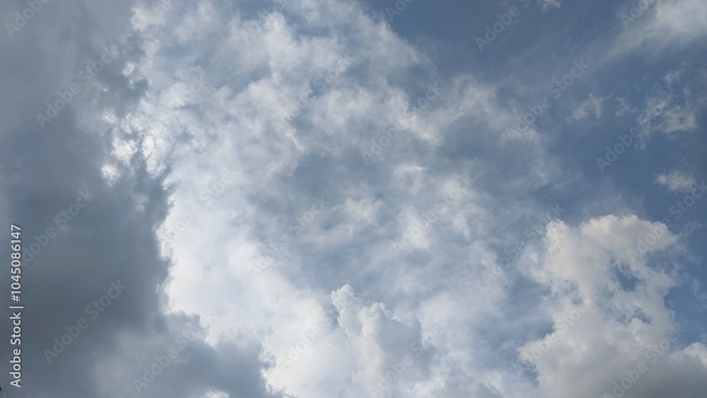 A cloudy sky with a mix of white and gray clouds. The clouds are large and fluffy. The sunlight is partially obscured by the clouds, creating a soft, diffused light. A cloudy sky with a mix of white and gray clouds. The clouds are large and fluffy. The sunlight is partially obscured by the clouds, creating a soft, diffused light.