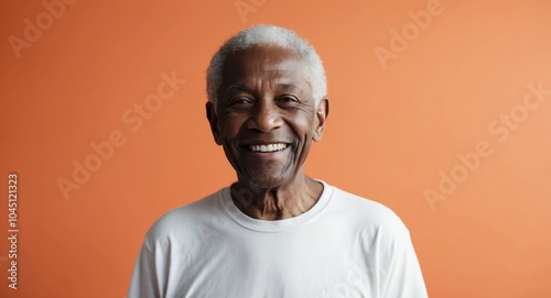 mixed race elderly man orange background wearing plain white tshirt smiling happy portrait