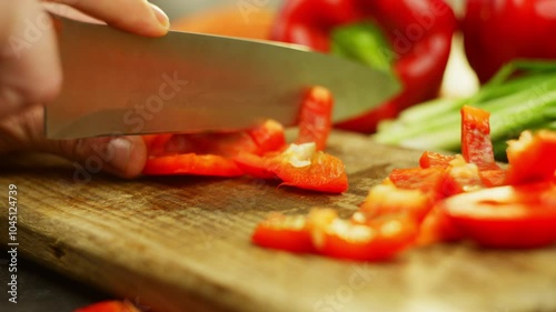 Slow motion video of slicing a red pepper with a knife on a cutting board. High quality 4k footage