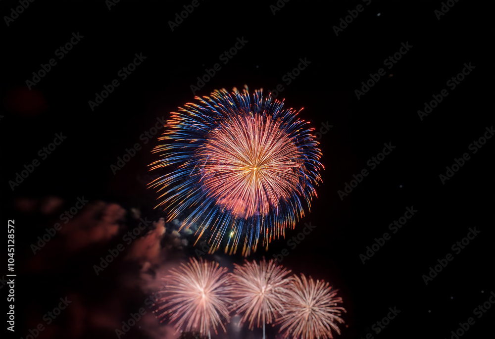 An isolated firework display bursts in a ring of colorful light against a black night sky. An isolated firework display bursts in a ring of colorful light against a black night sky.