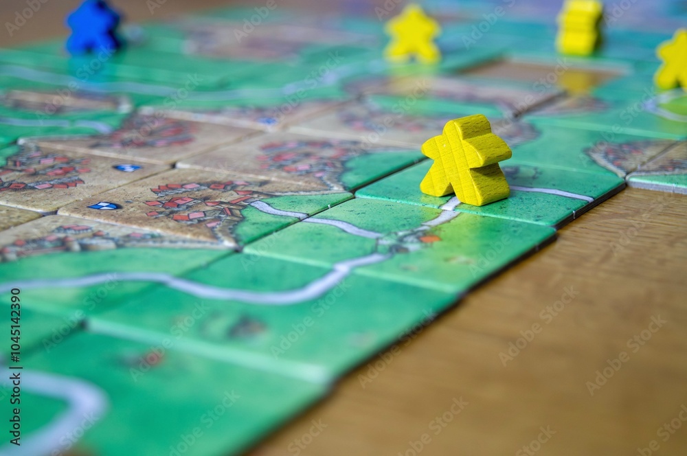 Close-up of yellow wooden game piece on a detailed board game surface, showing strategic pathways and positions in a tabletop setting Close-up of yellow wooden game piece on a detailed board game surface, showing strategic pathways and positions in a tabletop setting