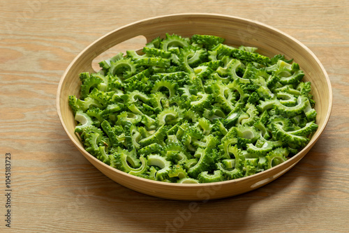 Bitter melon chunks prepared to cook or fry on a bamboo tray. Wooden background. photo