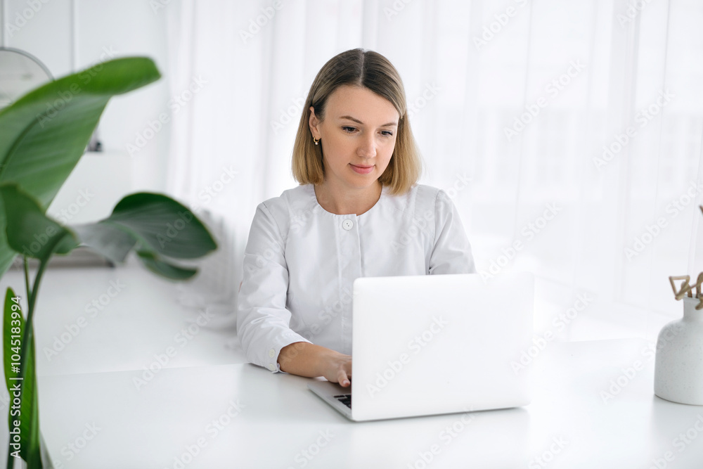 The doctor works at the computer at the table, printing the data of the patient's medical record The doctor works at the computer at the table, printing the data of the patient's medical record