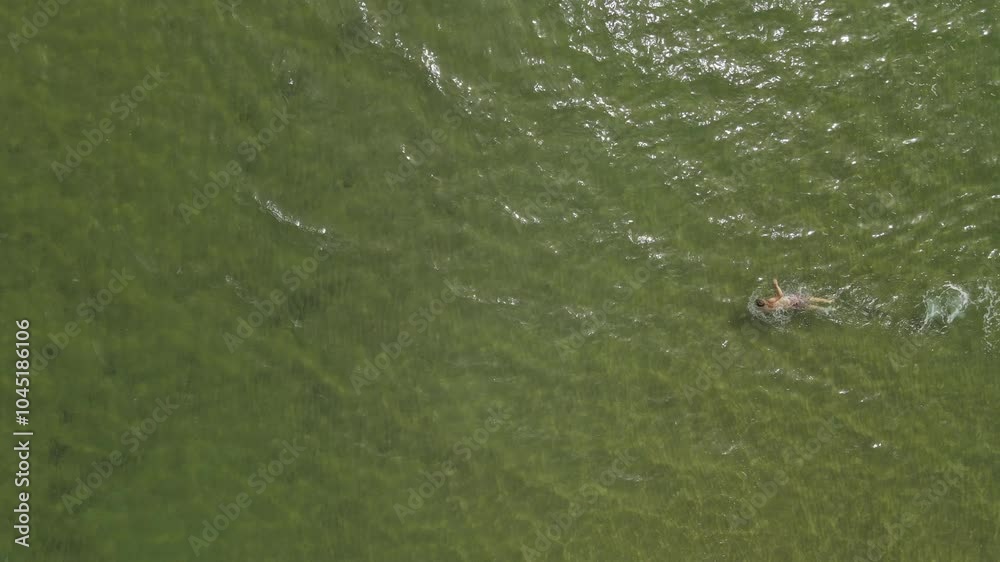young man swimming in the sea, top view