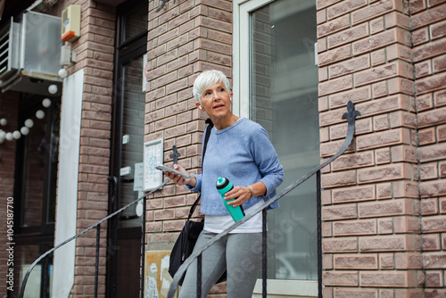 Wallpaper Mural Active senior woman using smartphone while leaving gym Torontodigital.ca