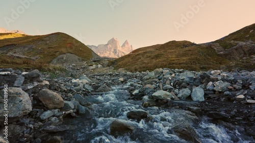 Landscape of iconic three peak mountain and stream flowing in Aiguilles d Arves among French Alps photo