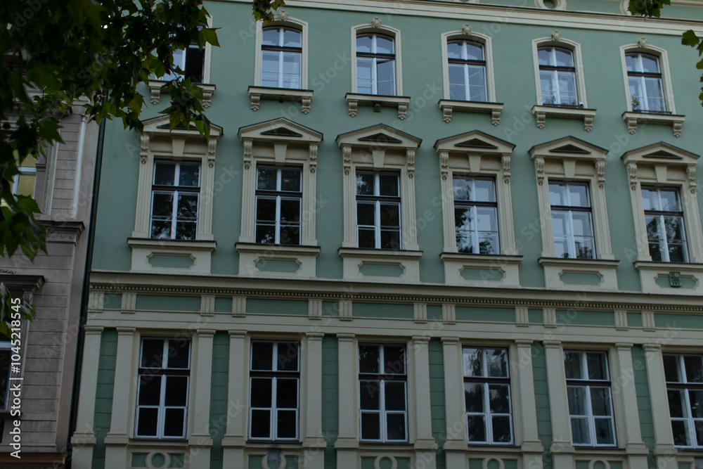 There is a striking green and white building that features an extensive array of windows, making it stand out in the cityscape There is a striking green and white building that features an extensive array of windows, making it stand out in the cityscape