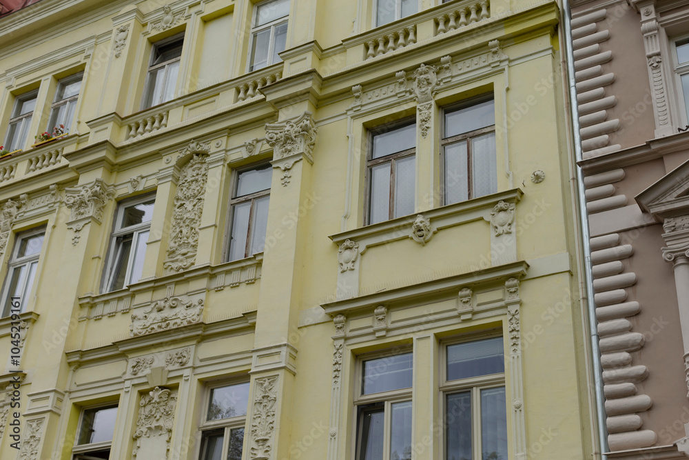 A bright yellow building that features an abundance of windows on its facade, giving it a charming and inviting appearance A bright yellow building that features an abundance of windows on its facade, giving it a charming and inviting appearance