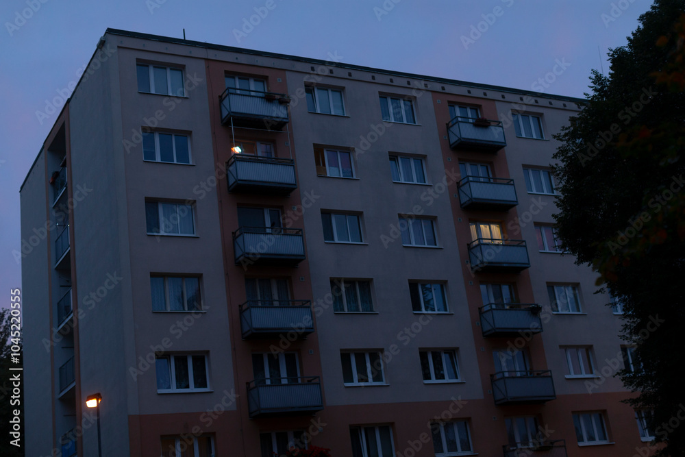A large modern building featuring numerous windows and elegant balconies that are beautifully illuminated during the night time hours A large modern building featuring numerous windows and elegant balconies that are beautifully illuminated during the night time hours