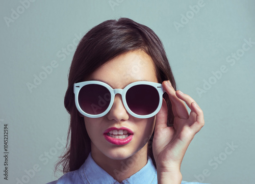 Studio, woman and chic with sunglasses for fashion, trendy style and edgy with hand for confidence. Female person, model or lipstick with accessory for beauty, magazine publication or gray background