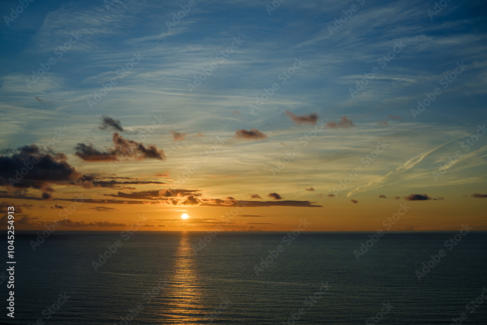 Naklejka premium Romantic colorful sunset at the sea. View of Beautiful glorious golden sunset and golden hour above the sea in evening.