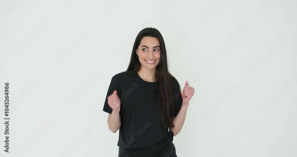 Cheerful young woman holds fists expressing satisfaction with positive news against white. Attractive female with pleasant smile shows joy Cheerful young woman holds fists expressing satisfaction with positive news against white. Attractive female with pleasant smile shows joy