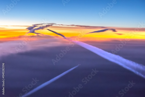 Aerial cockpit pilot view of aircraft, plane contrails, vapour cloud in pink landscape in air above earth