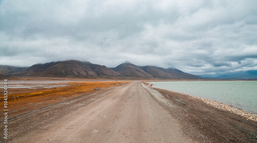 A scenic road along the coast of a fjord in Svalbard showcasing dramatic mountain landscapes A scenic road along the coast of a fjord in Svalbard showcasing dramatic mountain landscapes