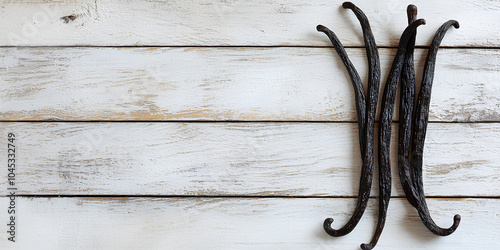 Bunch of black vanilla beans are on a wooden table. The beans are arranged in a way that they look like they are leaning on each other. Concept of warmth and comfort photo