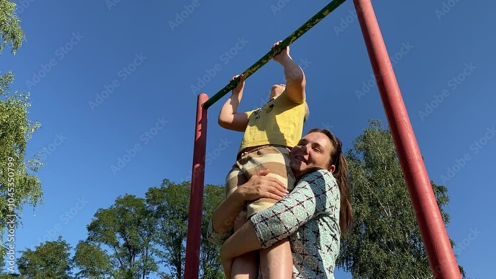 A young mother enjoys quality time with two elementary aged children at outdoor playground on a warm summer day. The family engages in fun activities, laughter, play, the most of leisure time together A young mother enjoys quality time with two elementary aged children at outdoor playground on a warm summer day. The family engages in fun activities, laughter, play, the most of leisure time together