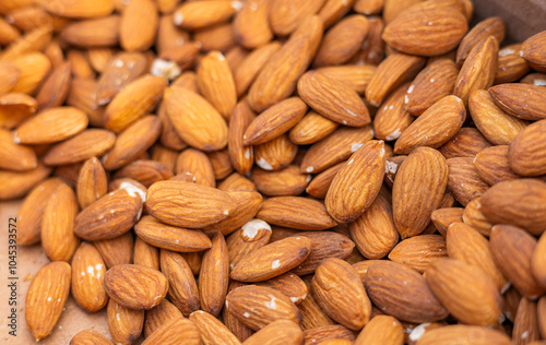 A large number of closely packed almonds with a light brown hue and textured surface. Relevant for food, agriculture, nutrition, or commerce discussions