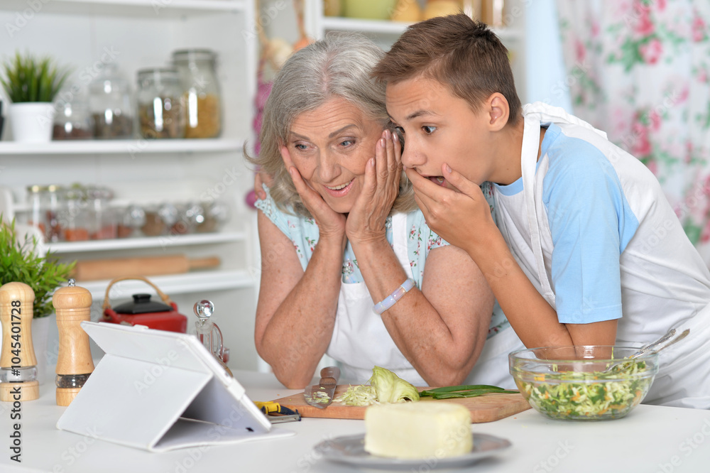 A young boy with his grandmother cooking in the kitchen A young boy with his grandmother cooking in the kitchen