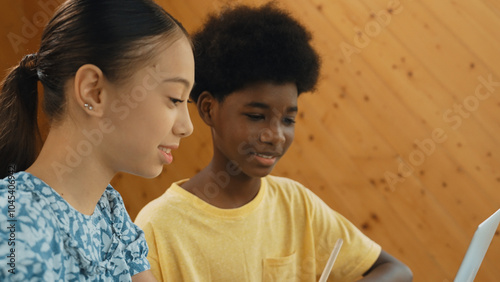 Site view of african boy and caucasian girl in casual cloth working together to coding prompt or programing system at table with laptop and electronic equipment at STEM technology class. Edification.