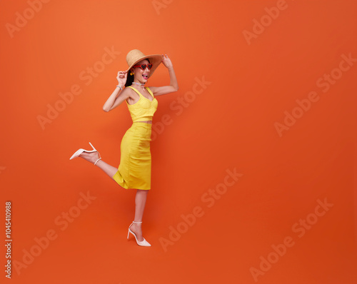 Happy young sexy woman slim body wear yellow swimsuit straw wide brim hat posing isolated on orange color background studio. Summer hotel pool sea rest sun tan concept