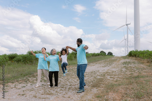 This family is relaxing in a windmill field surrounded by nature. Most of them are wearing blue shirts in line with the concept of environmental conservation.