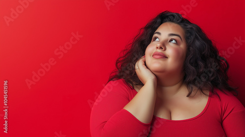 Curvy woman in a red shirt looking thoughtfully upwards, symbolizing reflection, positivity, and body confidence in a bold red setting