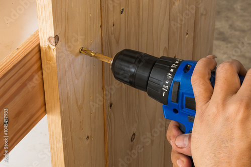 Close up scene the  power screw driver working with wooden plank. photo