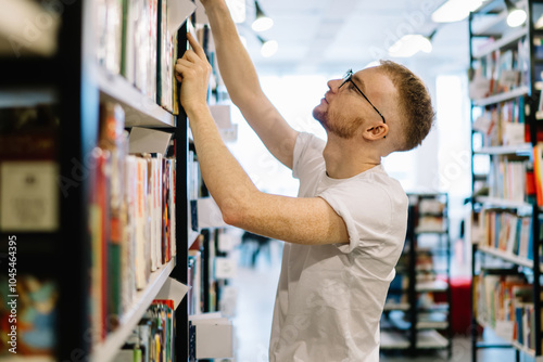 Student taking book from bookshelf in library