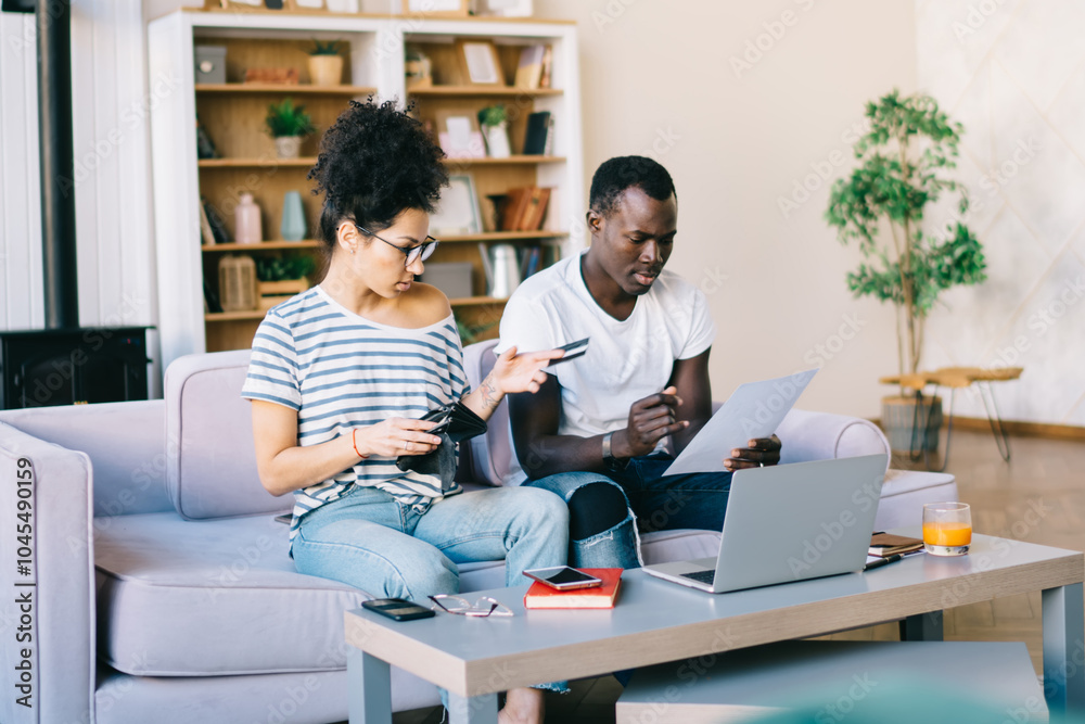 Multiethnic couple with document and credit card at home Multiethnic couple with document and credit card at home