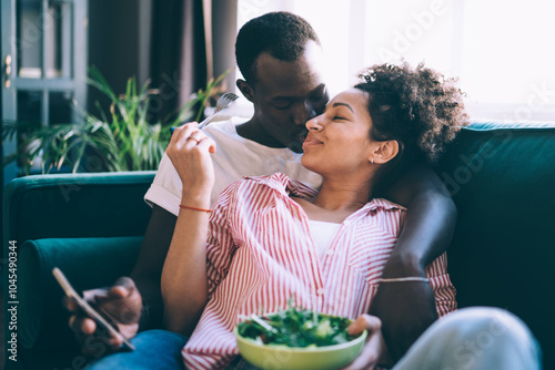 Tender multiethnic lovers indulging in caresses on sofa at home photo