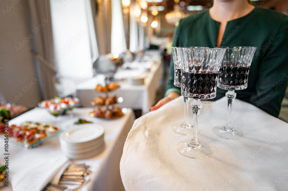 A waiter elegantly serves red wine at a banquet, with a blurred background of appetizers and guests, capturing the essence of fine dining and hospitality. Perfect for illustrating upscale restaurant A waiter elegantly serves red wine at a banquet, with a blurred background of appetizers and guests, capturing the essence of fine dining and hospitality. Perfect for illustrating upscale restaurant