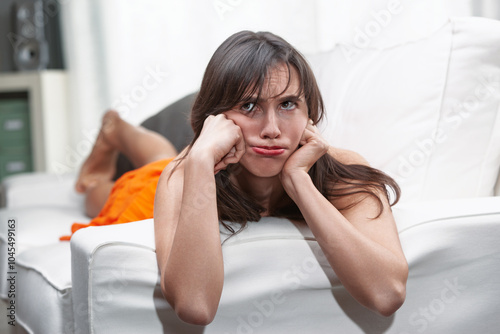 Young woman lying on sofa making a bored expression