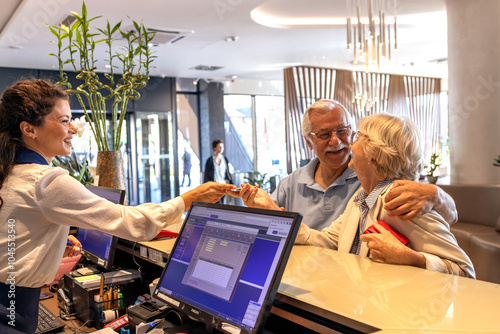 Couple of senior booking room at the hotel reception desk
