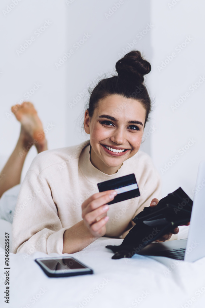 Gorgeous woman showing credit card while lying on bed Gorgeous woman showing credit card while lying on bed