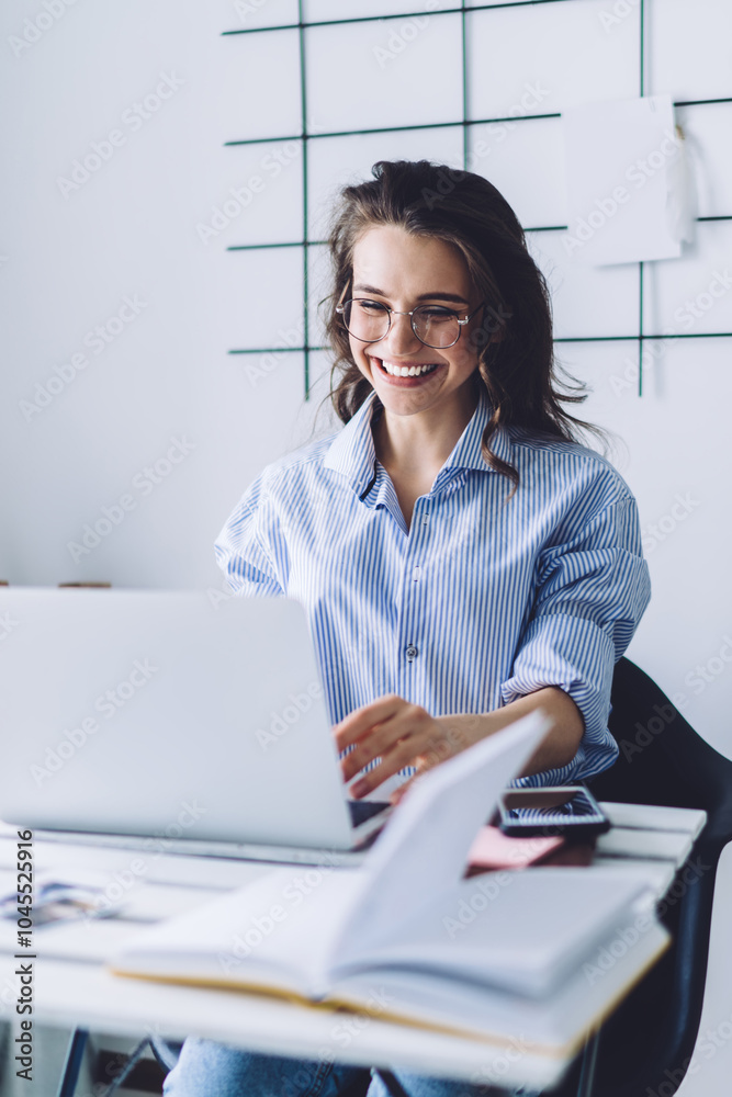 Happy woman working at laptop while sitting at desk