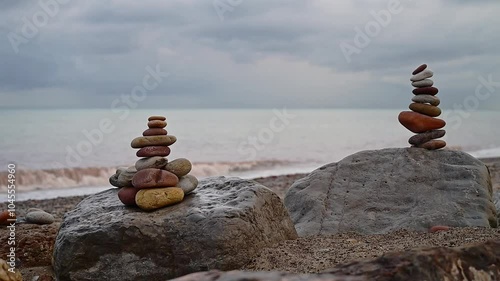 Pair of apachetas, stone cairns by the sea on a reddish autumn afternoon, Spain photo