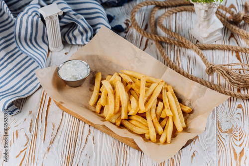 Golden French fries with a side of creamy dip, perfect for snack lovers photo