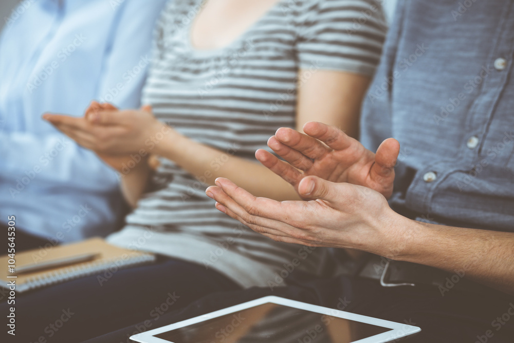 Fototapeta premium Business people clapping at meeting or conference, close-up of hands. Group of unknown businessmen and women in modern white office. Success teamwork, corporate coaching and applause concept