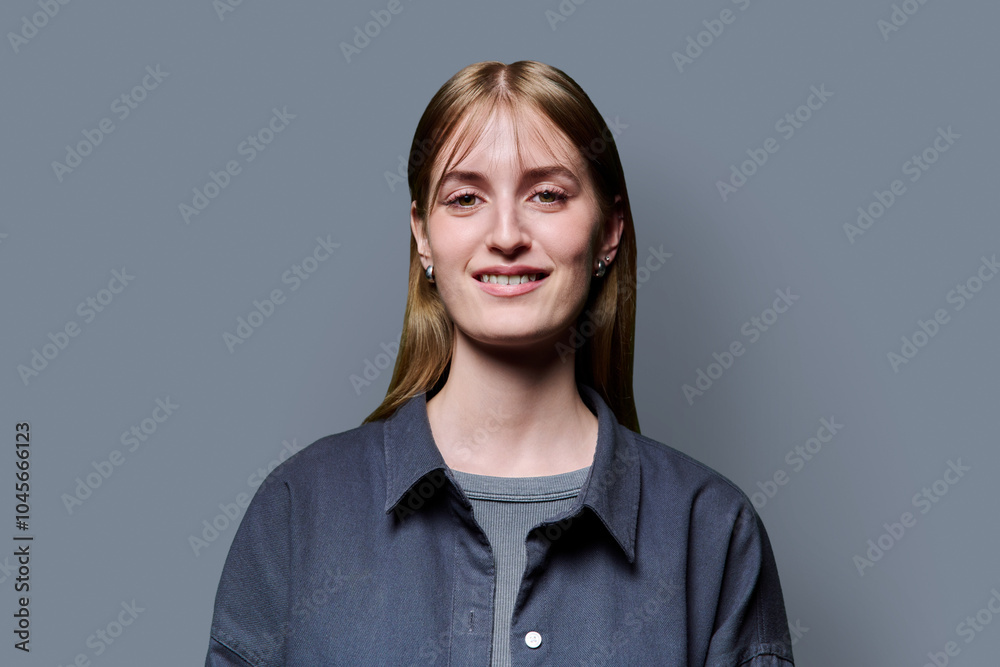 Obraz premium Portrait of beautiful young woman with blond hair looking at camera on grey background