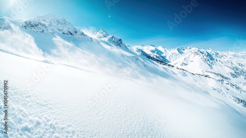 A snowy mountain range stretches across the horizon, with its peaks bathed in sunlight under a deep blue sky, presenting a striking natural panorama. photo