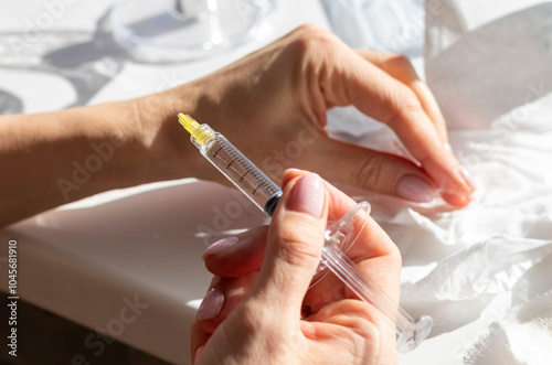 Woman performing mesotherapy, bio revitalization procedure, injecting medecine in her hand. Cosmetics photo