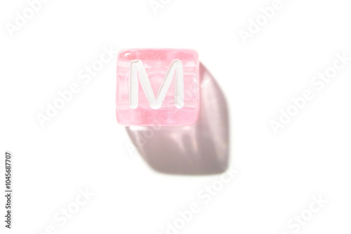 Pink transparent cube with white letter m isolated on clean white background with shadow photo