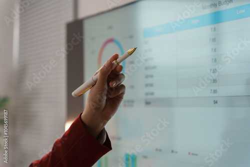 Businesswoman is pointing at a digital interactive whiteboard showing financial data during a presentation