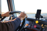 View of a truck driver's hand on the steering wheel of a truck driving on a country road