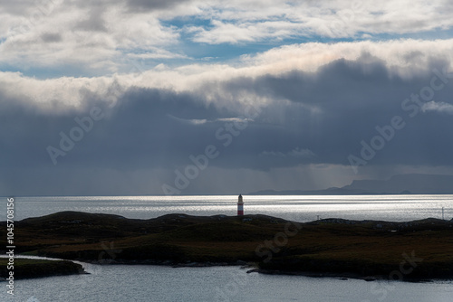 Looking out across the Minch to the Isle of Skye, the red and white Eilean Glas Lighthouse on the east coast of the island of Scalpay in the Outer Hebrides, Scotland, UK photo