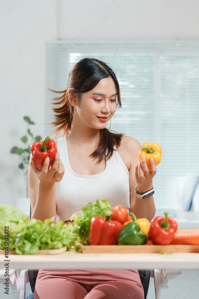 Young woman is smiling while choosing a bell pepper for her salad, surrounded by fresh vegetables on a table Young woman is smiling while choosing a bell pepper for her salad, surrounded by fresh vegetables on a table