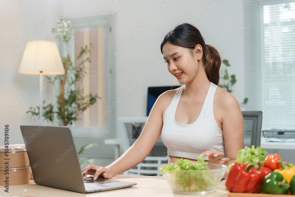 Young asian woman enjoying a healthy salad while working on her laptop, embracing a balanced lifestyle Young asian woman enjoying a healthy salad while working on her laptop, embracing a balanced lifestyle